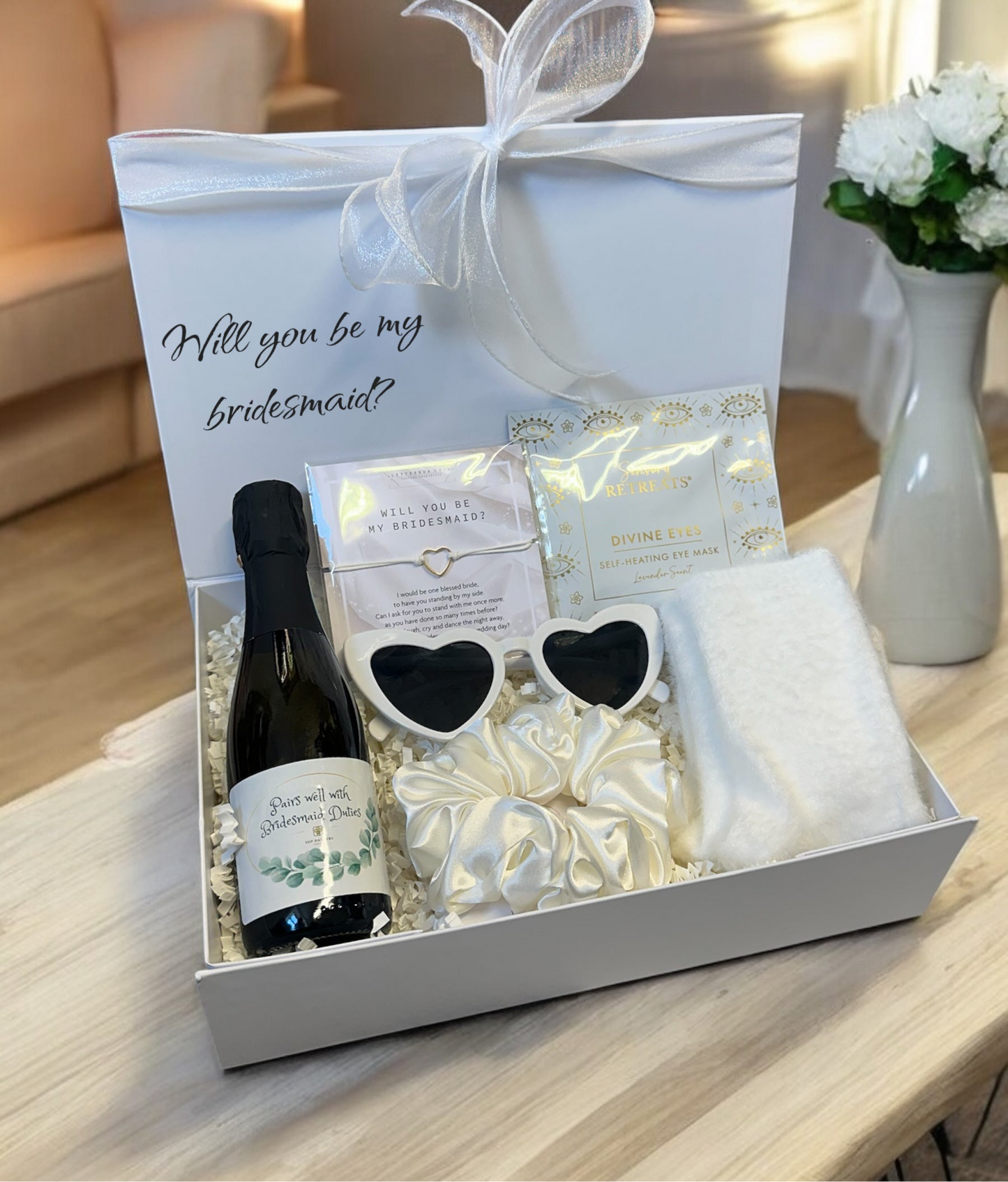 Be My Bridesmaid hamper with pink Prosecco, bracelet, heated eye mask, house socks, satin scrunchie, and heart sunglasses.