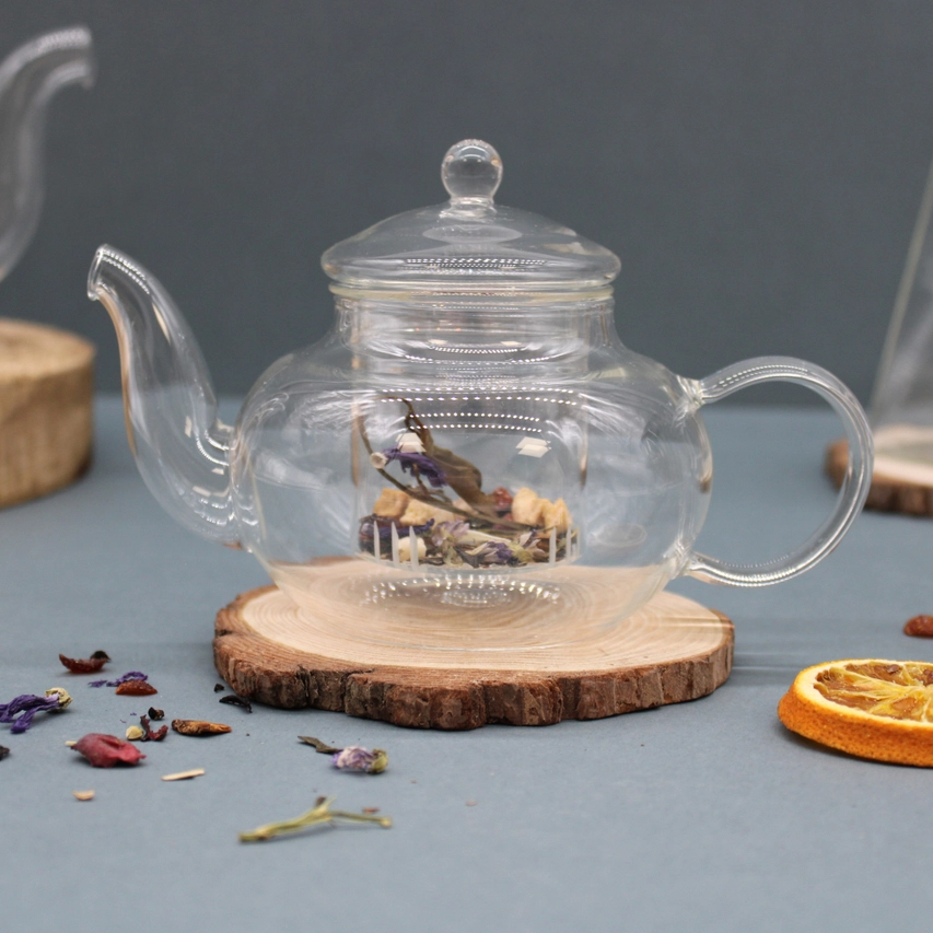 Pearl decorated glass infuser teapot with stainless steel infuser on wooden coaster.