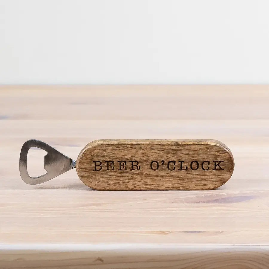 Wooden bottle opener with 'BEER O'CLOCK' engraving on a light wooden surface.