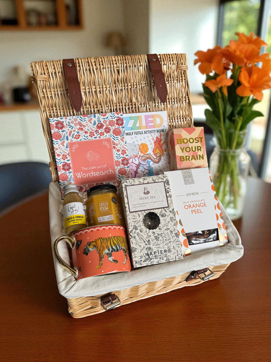 Brain Boost Hamper featuring puzzle books, brain cards, ginger honey turmeric shots, study blend tea, orange peel chocolates & a gold tiger-print mug.