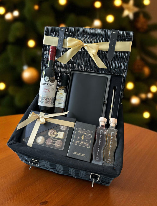 Christmas Delights Hamper with bottle of red wine, handmade Italian leather journal, Hamiltons chocolates, Oxton Liqueurs, and True Grace Manor Christmas room spray.
