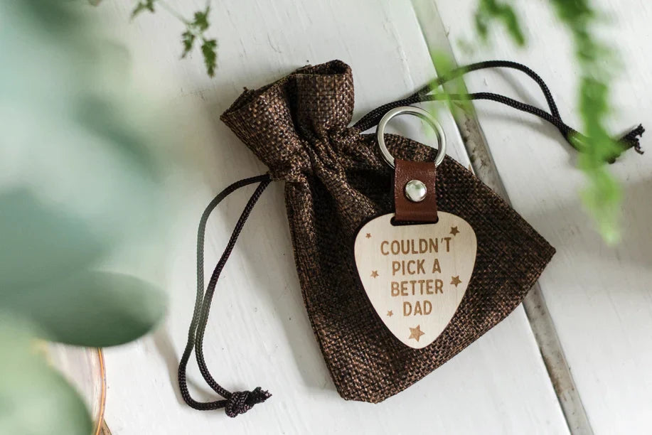 Better Dad wooden keychain shaped like a guitar pick with leather strap and silver ring.