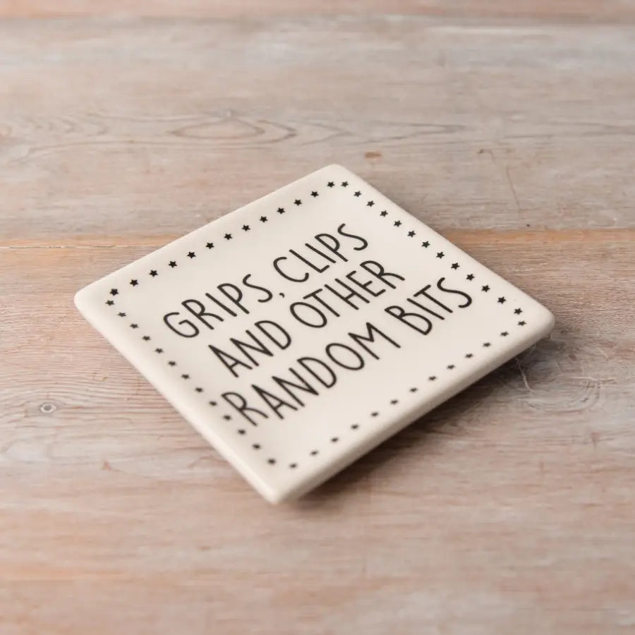 Grips Ceramic Dish in beige with decorative text on wooden surface.