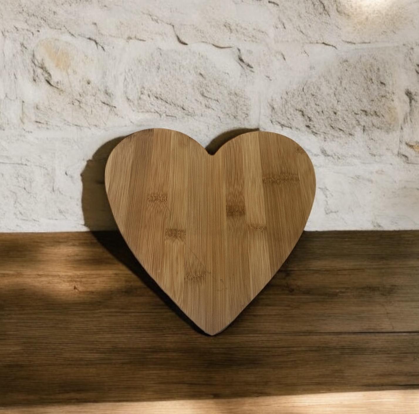 Heart-shaped wooden serving board on wooden surface against stone wall.