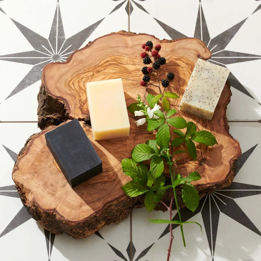 Men's Charcoal Beard Bar on a decorative wooden display with other soap bars and greenery.