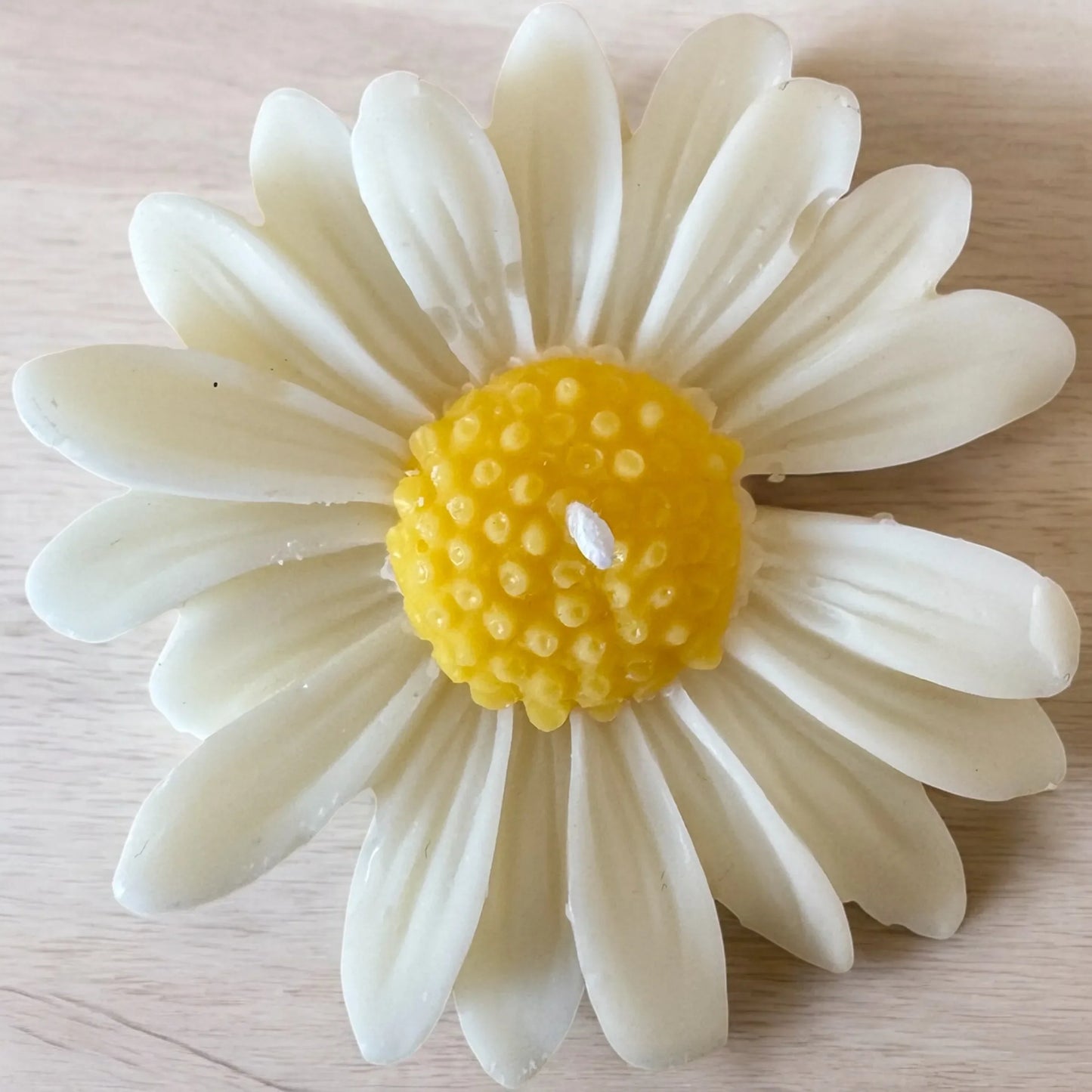 White Daisy Mini Candle shaped like a daisy on a wooden surface.