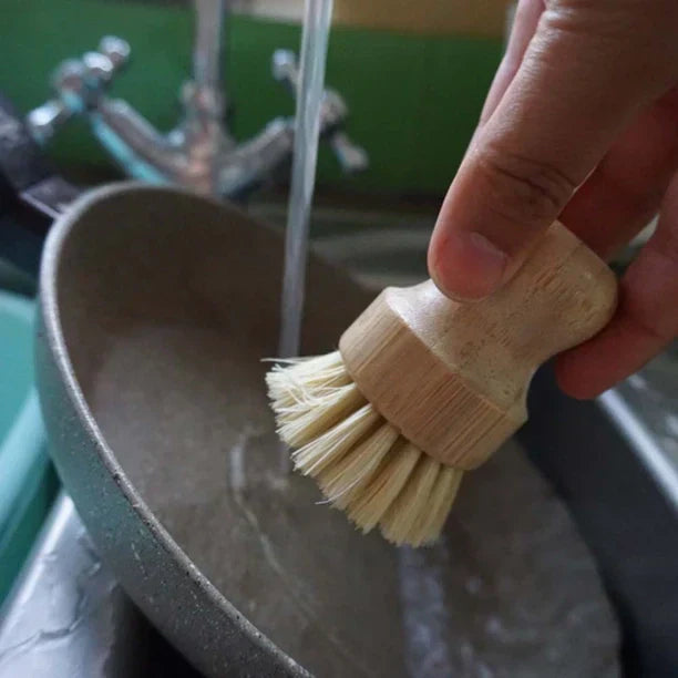 Eco-friendly bamboo pot brush with sisal bristles, ergonomic handle in use.