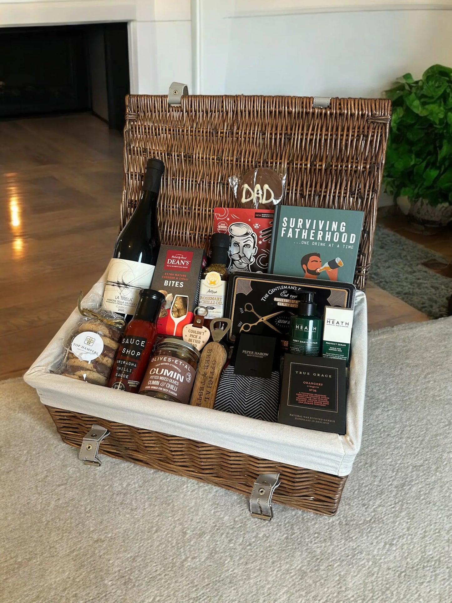 Gift basket labeled "Super Dad" filled with wine, snacks, grooming items, and a book for celebrating fatherhood.