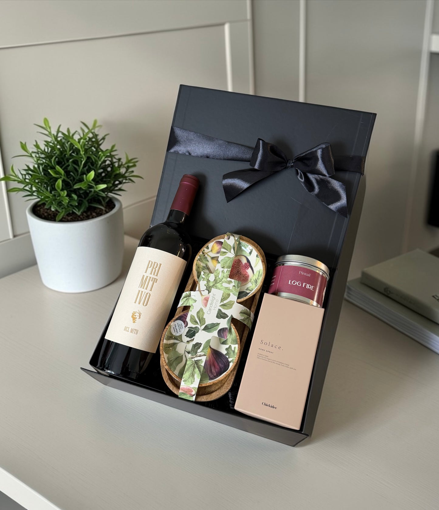 New home gift hamper with Primitivo red wine, fig and pear dipping bowls, log fire candle and clay home spray.