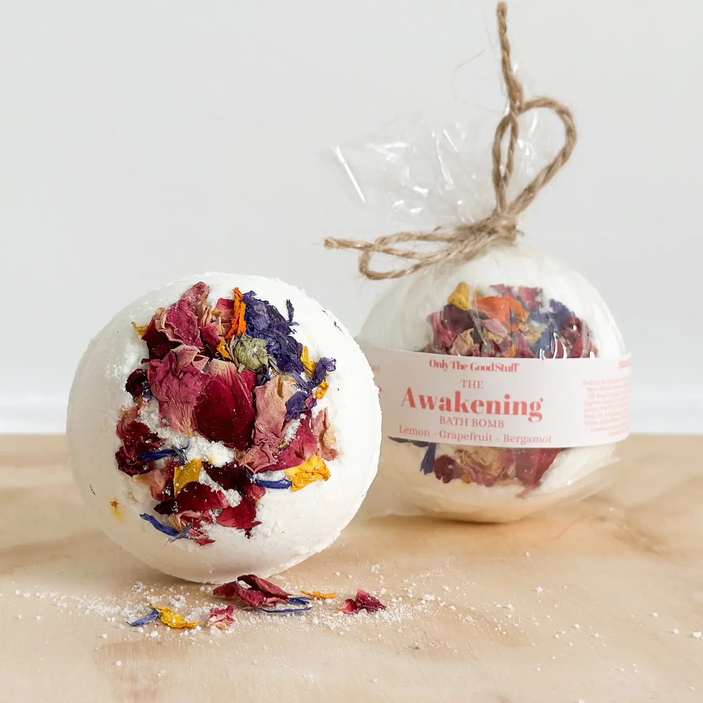 The Awakening Bath Bomb with dried floral accents on wooden surface.