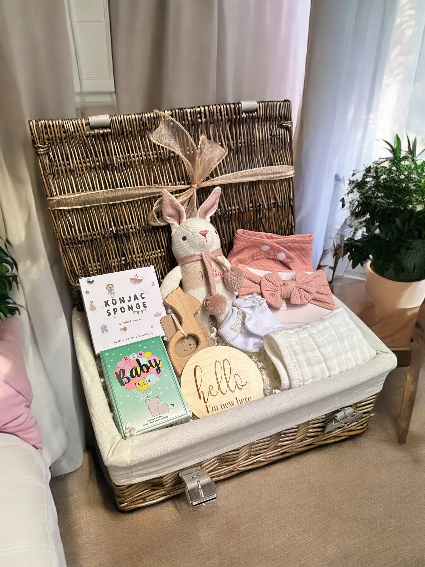 Baby Bliss Bundle with photo prop, wooden giraffe teether, pink socks, konjac sponges, bunny rattle, bib, and muslin cloth.