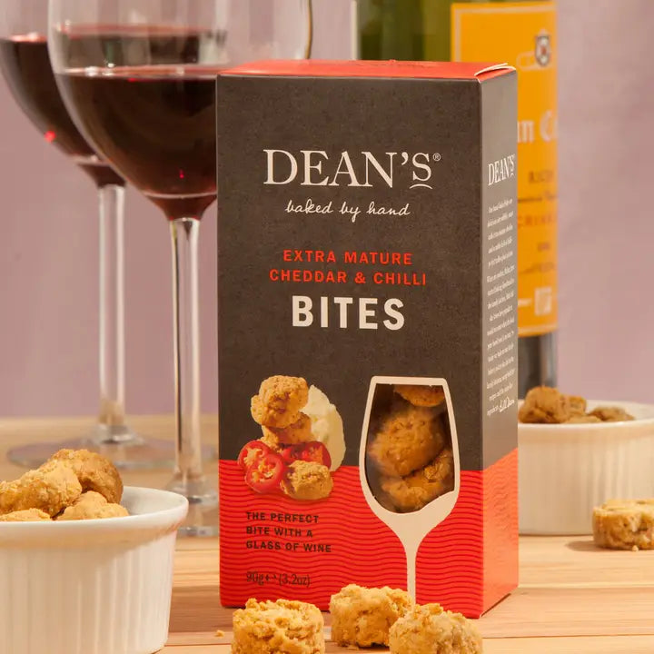 Extra Mature Cheddar with Chilli Biscuit Bites packaging with wine glasses in the background.