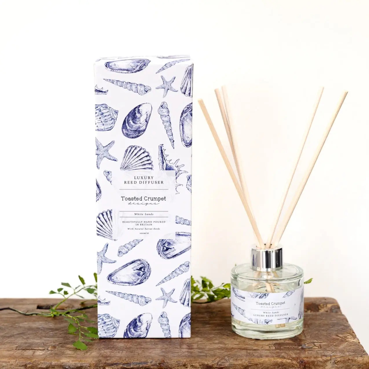 White Sands Coastal Reed Diffuser with seashell-themed packaging and reeds on a wooden surface.