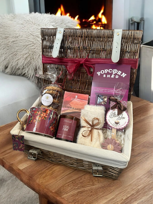 Cosy Night In hamper with hot chocolate, biscuits, popcorn, decorative mug, fluffy socks, candles, and bath soak.