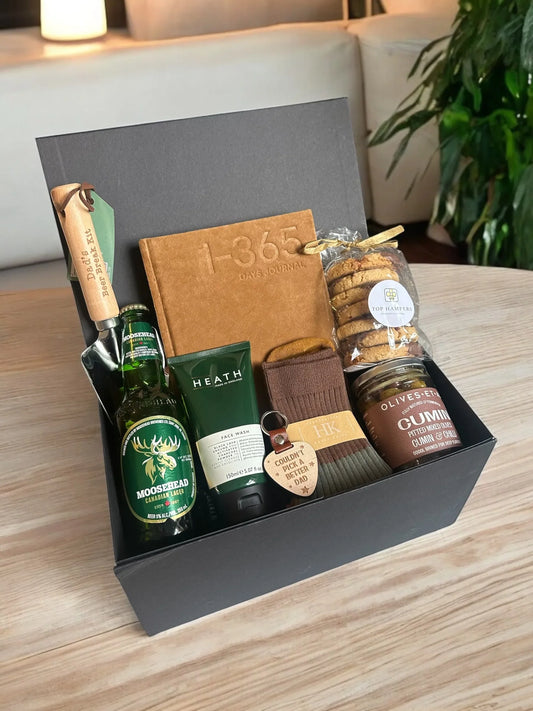 Dad's Gift Box with lager, snacks, and accessories on a wooden table.
