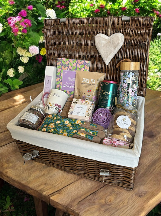 Gift basket with calming products, wildflower seeds, floral mug, gardening gloves, candles, tea, and chocolates for Mum.