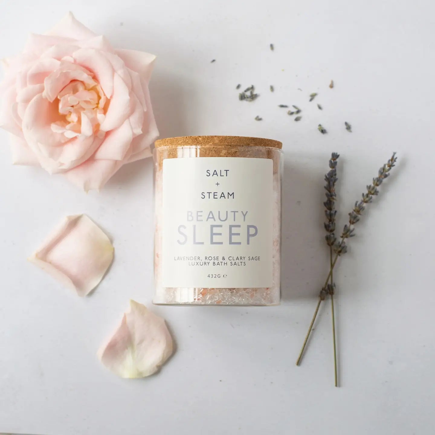 Beauty Sleep Lavender & Rose Bath Salts in glass jar with lavender sprigs and rose petals.