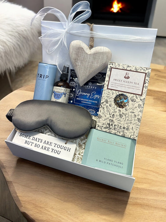 Rest and Recover Hamper with silk eye mask, magnesium oil spray, ylang ylang bath infusion, CBD drink, Sweet Sleeps tea, and inspirational signs.