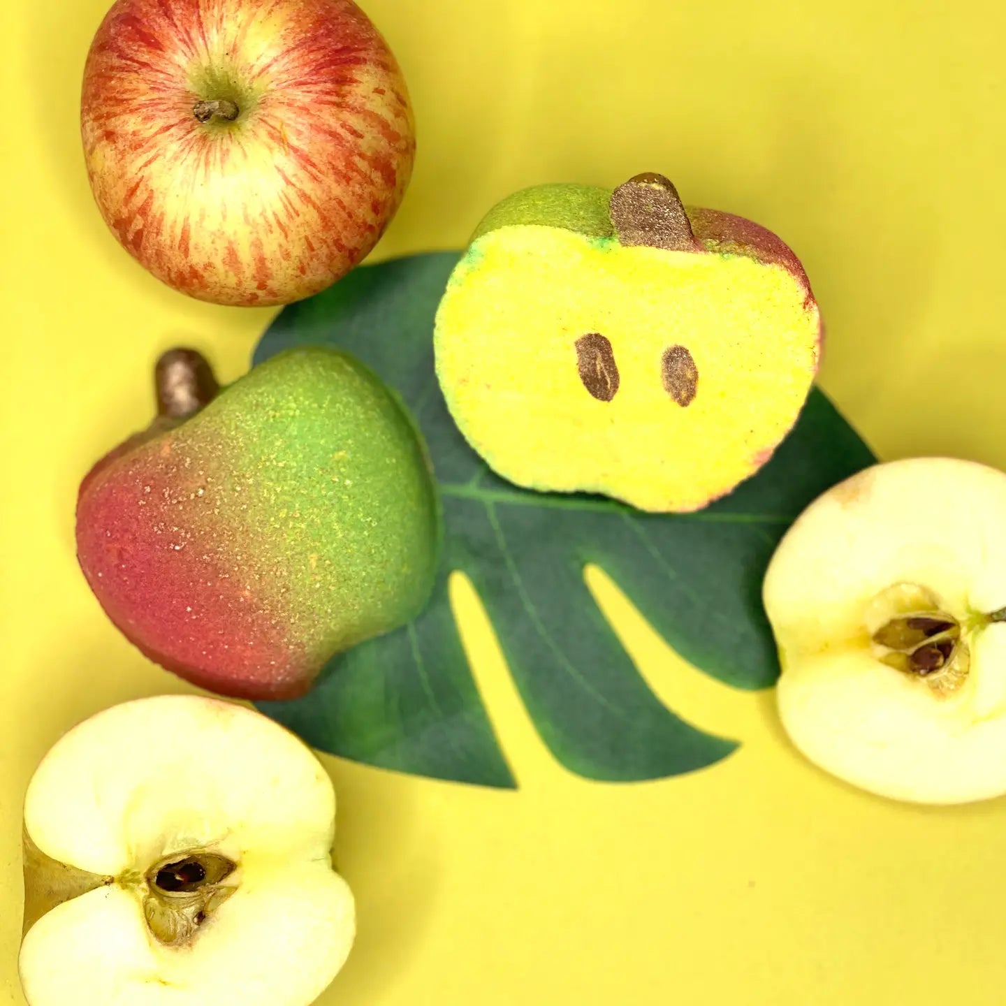 Handmade "An Apple A Day" bath bomb shaped like an apple on a yellow background.