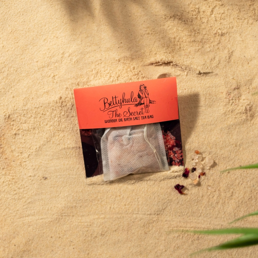 Luxurious Secret Wonder Oil Bath Salts Tea Bag on sandy background, featuring natural Himalayan salts and nourishing oils for a soothing soak.