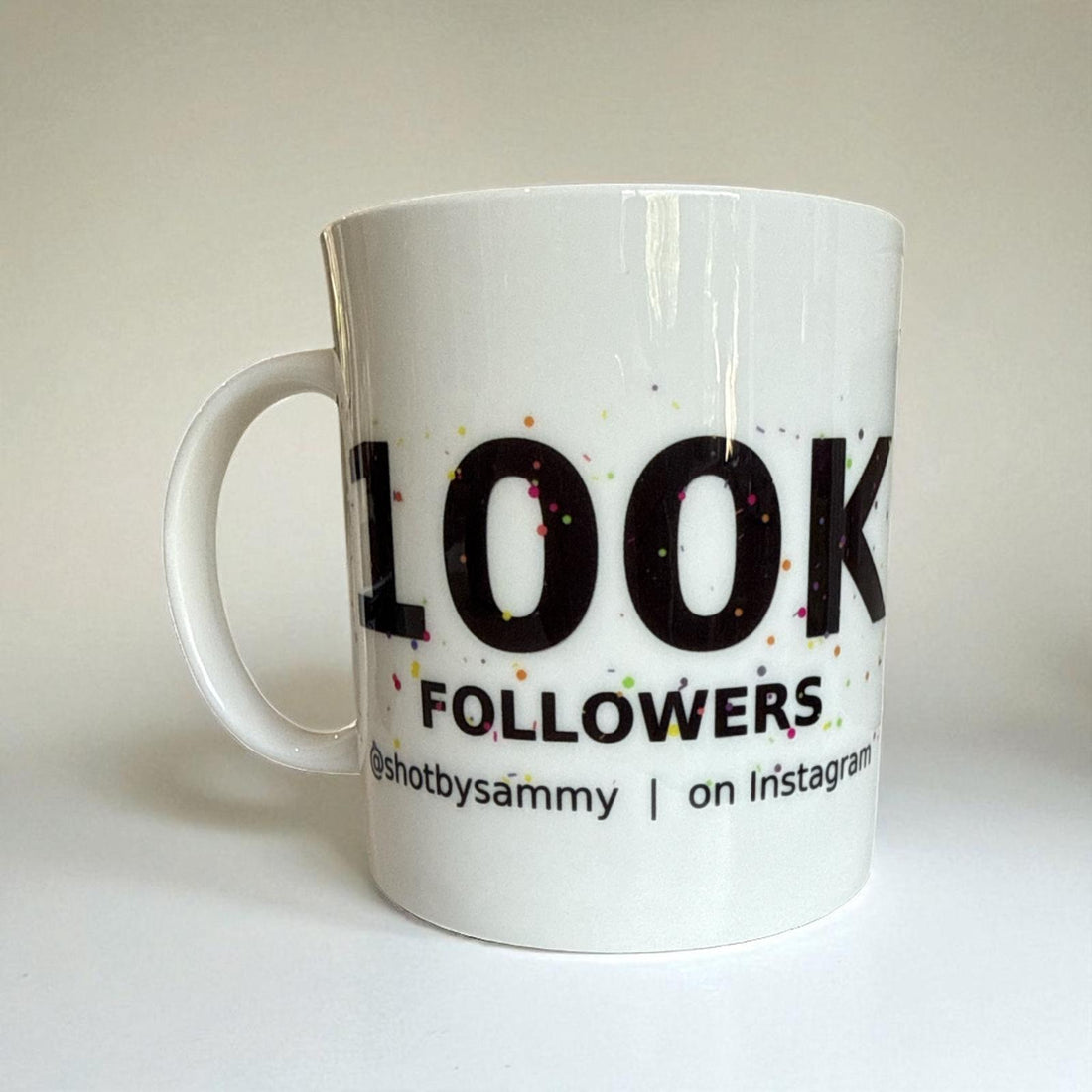 A white mug featuring the text '100k Followers' in bold, celebrating a social media milestone.