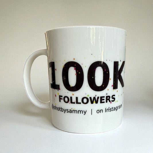 A white mug featuring the text '100k Followers' in bold, celebrating a social media milestone.