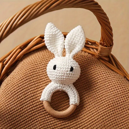 Crochet rabbit baby rattle with wooden handle in white.