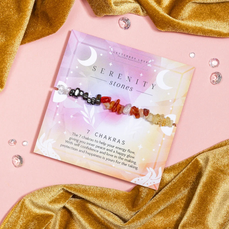 Colourful 7 Chakras crystal chip wish bracelet on a serene pink and gold background.