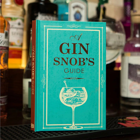 Hardback book titled "A Gin Snobs Guide" with a turquoise cover in a bar setting.