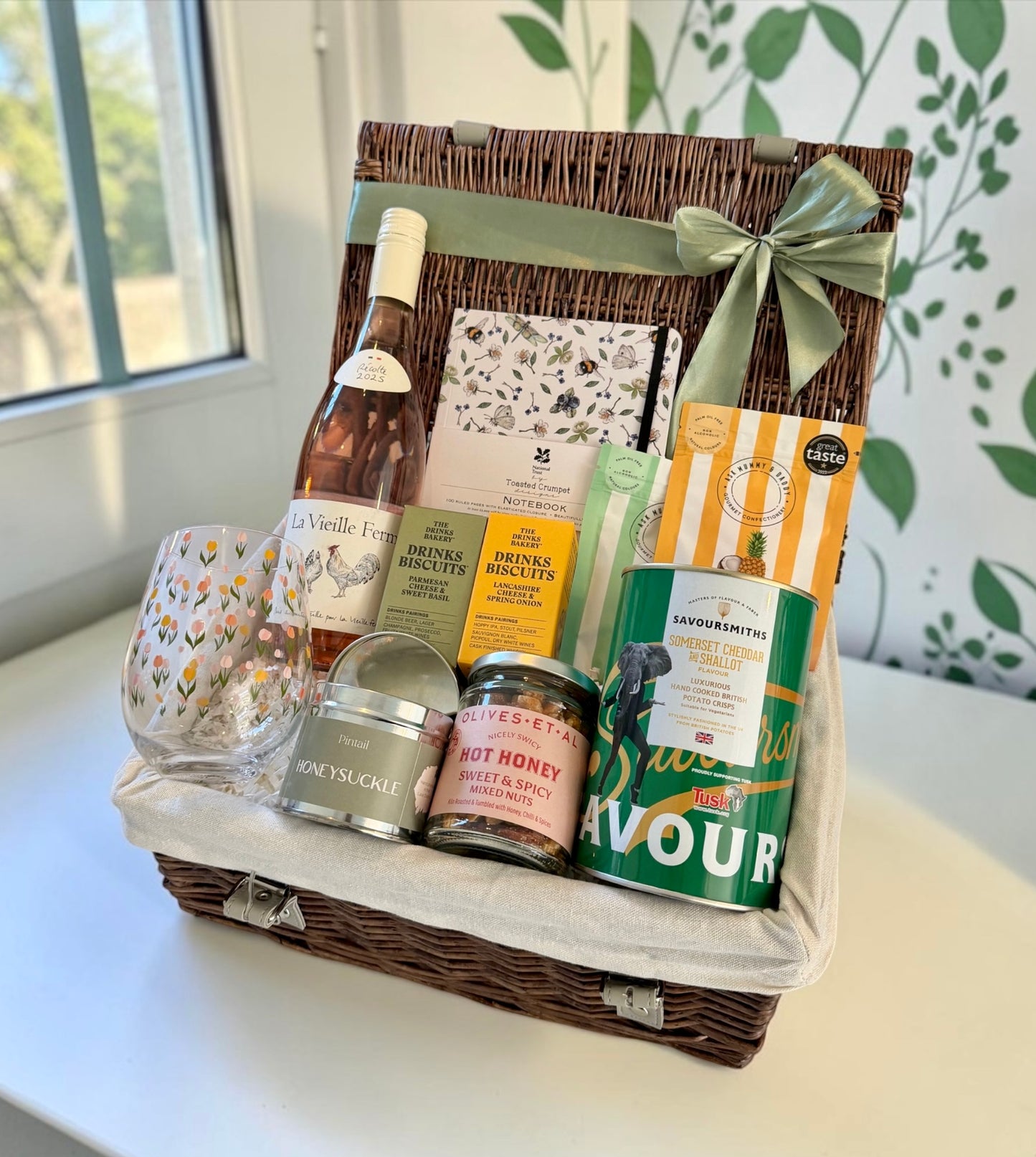 Gift basket with wine, snacks, and other items on a table.