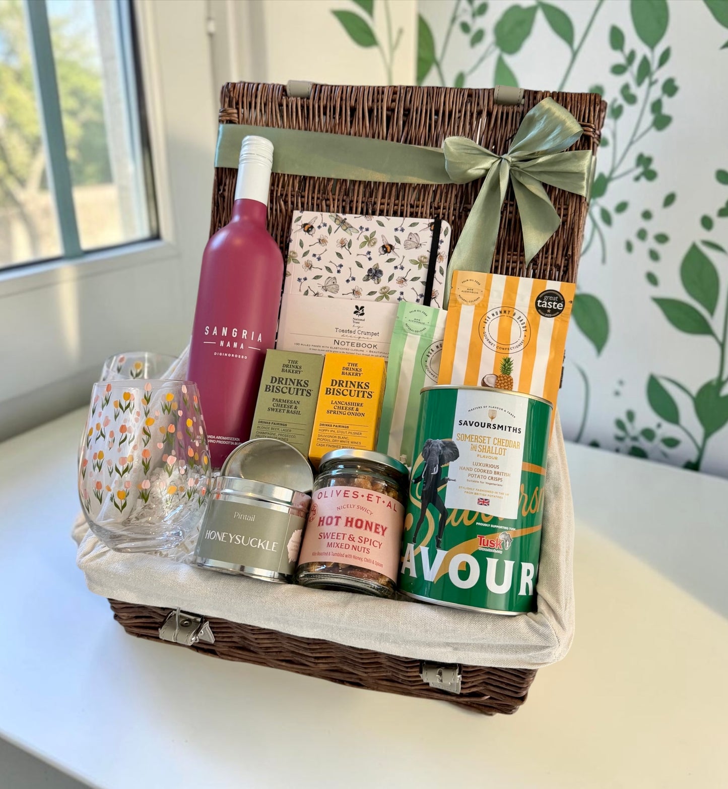 Gift basket with a bottle of wine, snacks, and other items on a table.