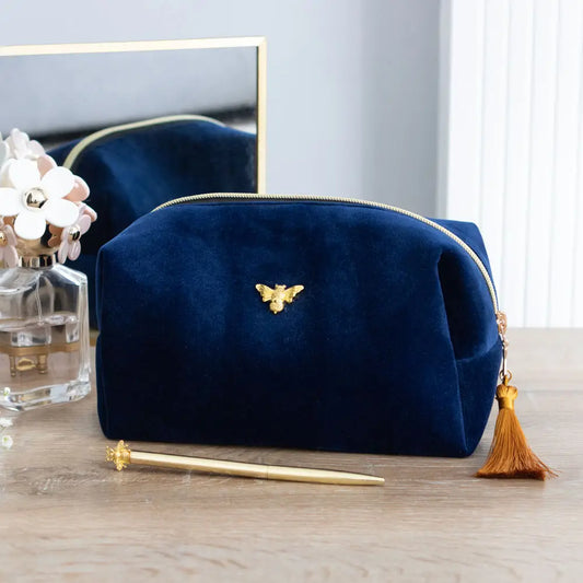 Bee-Utiful Velvet Makeup Bag with gold bee accent and tassel on a table.