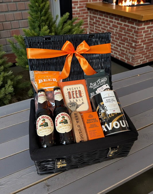 Gift basket with beer bottles and packaging on a wooden surface outdoors.