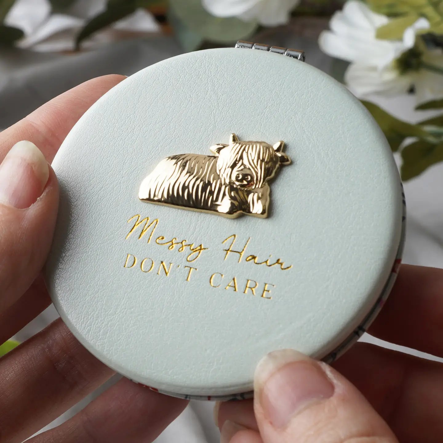 Elegant White Compact Mirror with gold Highland Cow design and “Messy Hair, Don’t Care” slogan, presented in a stylish gift box.