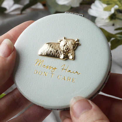 Elegant White Compact Mirror with gold Highland Cow design and “Messy Hair, Don’t Care” slogan, presented in a stylish gift box.