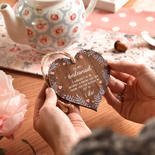 Heart shaped wooden bridesmaid thank you plaque with blue leaves, blush flowers, and jute string.