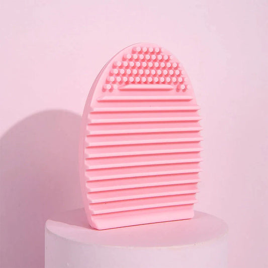 Pink silicone makeup brush cleaning tool with multi-textured surface for removing makeup and oils.