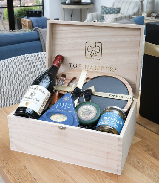 Gift box from Top Hampers containing a bottle of wine, cheese, slate and wooden cheese board and olives. 