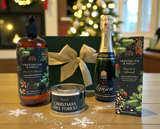 Festive gift set with Lanson Champagne, Frosted Fir & Holly wash and hand cream, and a Christmas Tree Forest candle in a green box with gold bow.