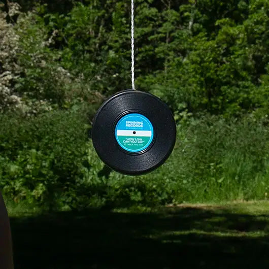 Classic vinyl yoyo toy hanging outdoors with greenery in the background.