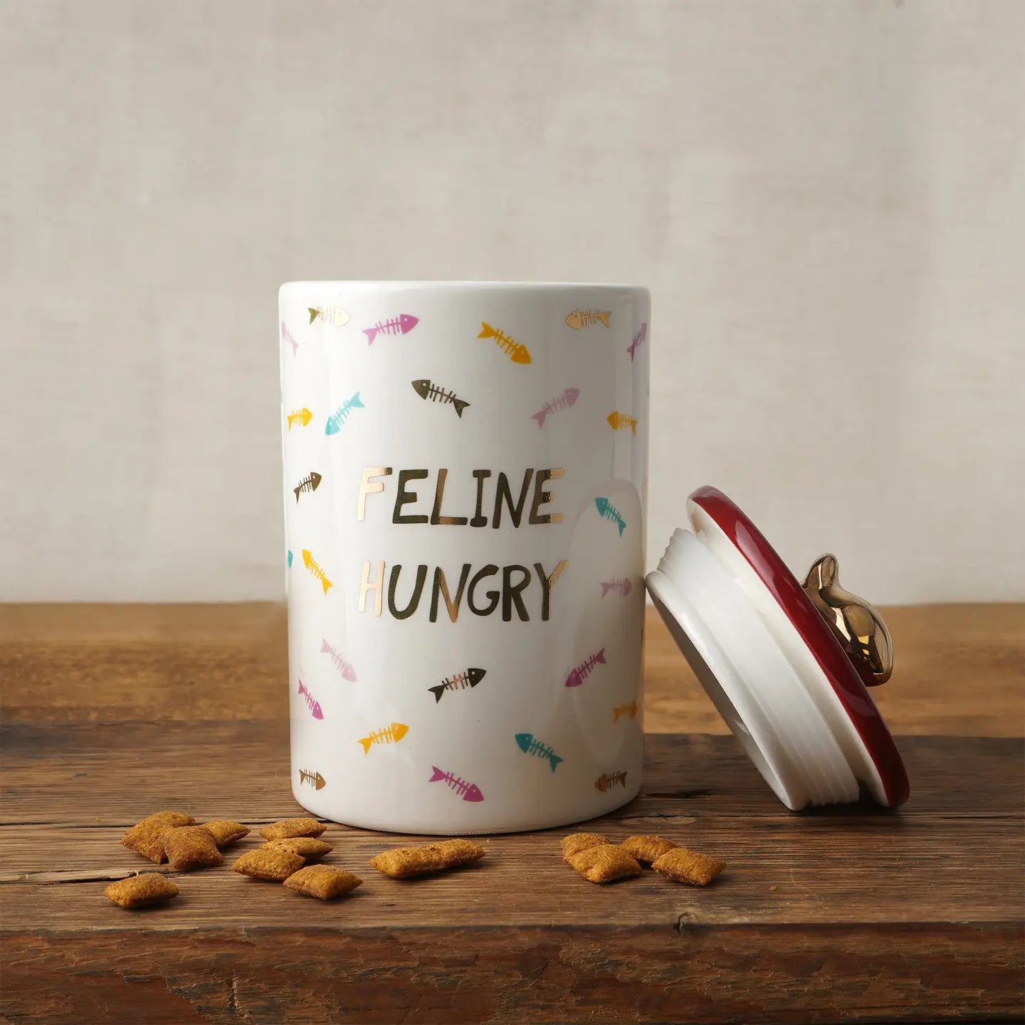 Ceramic cat treat jar with "Feline Hungry" slogan and golden fish lid.