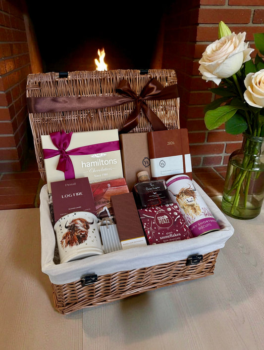 Luxury winter gift hamper featuring candle, chocolates, Bramble Whisky liqueur, journal, Highland Cow mug, and seasonal self-care items.