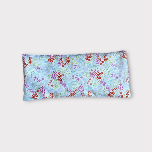Relaxing aromatherapy eye pillow with floral design on light background.
