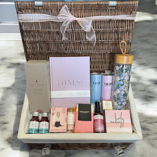 Luxury gift set for female fitness fanatic with journal, health shots, hand wash, CBD drinks, water bottle, bath salts, muscle oil, sports socks, and bath melt.