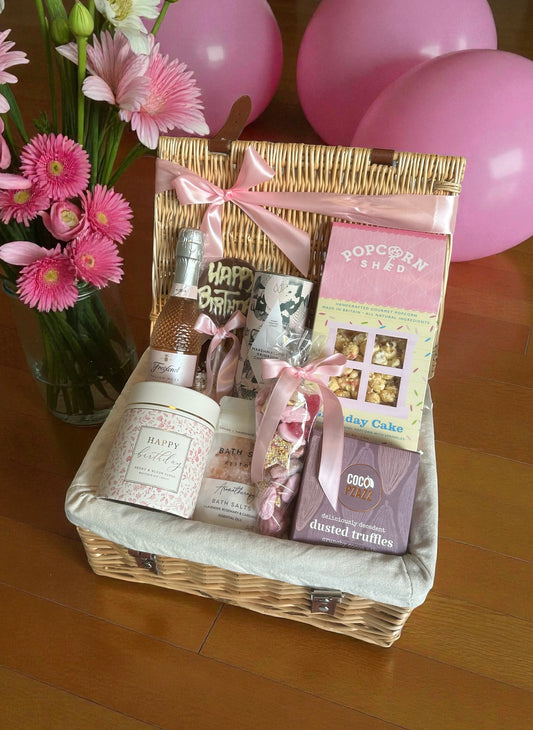 Gift basket with pink flowers and balloons on a wooden surface