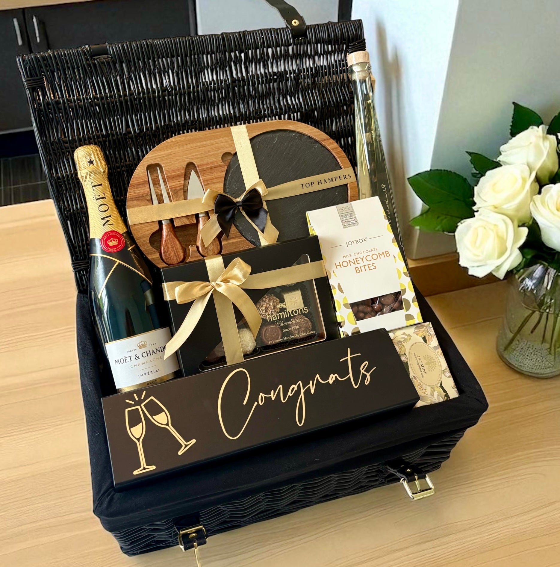 Congratulations gift box with champagne, chocolates and a cheese serving board.