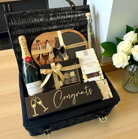 Congratulations gift box with champagne, chocolates and a cheese serving board.