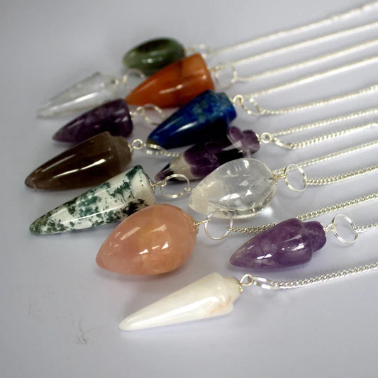 Various colorful crystal pendulums with silver chains, ideal for dowsing, healing, and divination.
