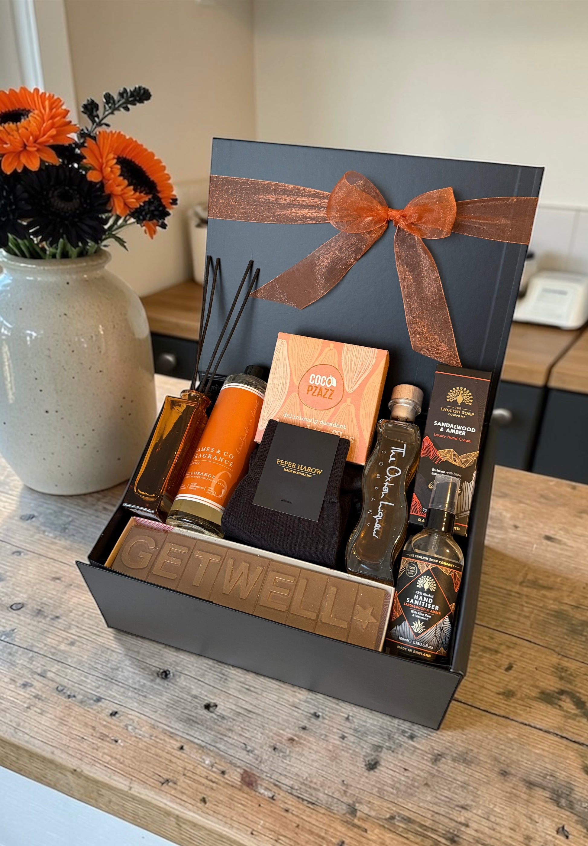 Get well gift hamper with truffles, rhubarb gin liqueur, hand cream, diffuser or bath bomb and Peper Harow socks.