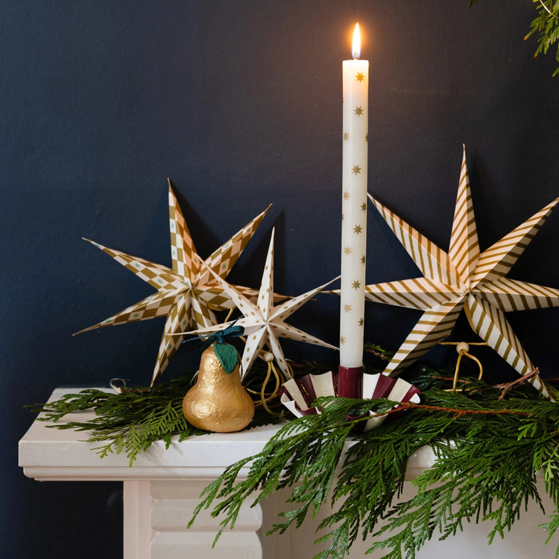 Set of two ivory Christmas dinner candles decorated with metallic gold stars.